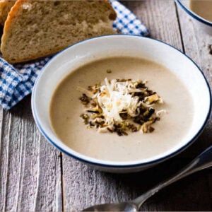 potato and leek soup served in a white bowl with some fresh bread in the background