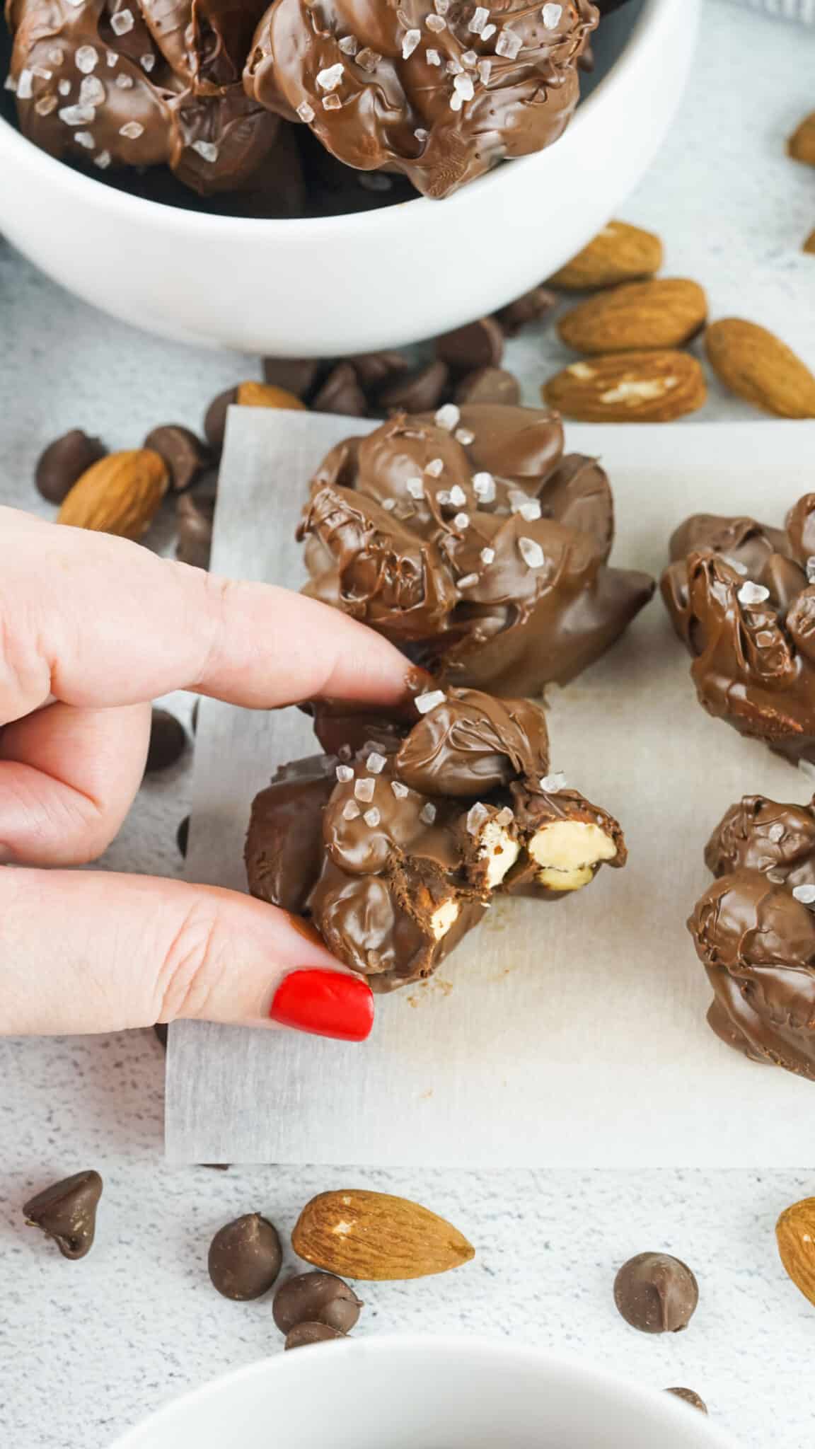 Chocolate clusters being taken from a bowl and placed on some parchment paper to rest