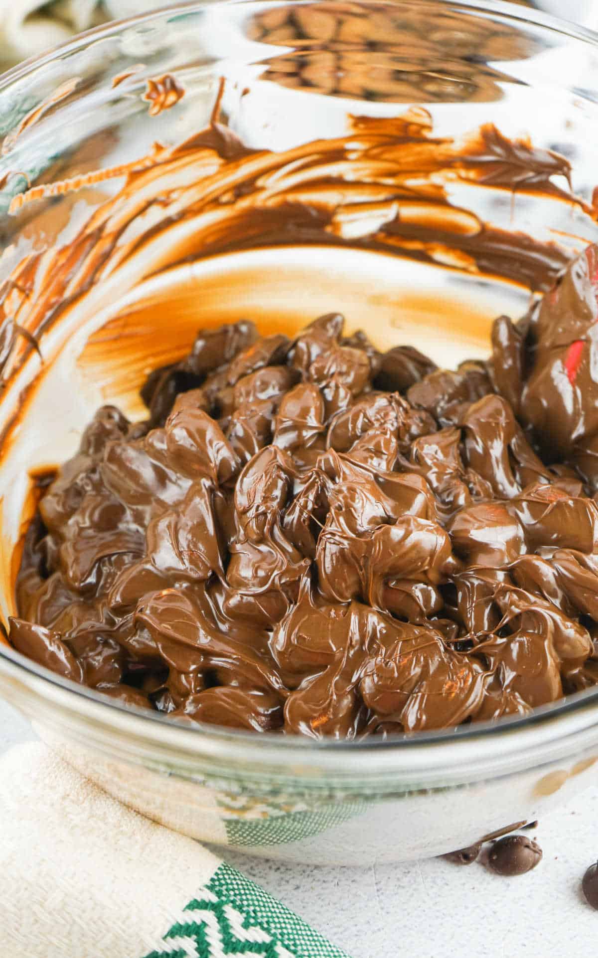 Almonds coated in melted chocolate in a glass bowl