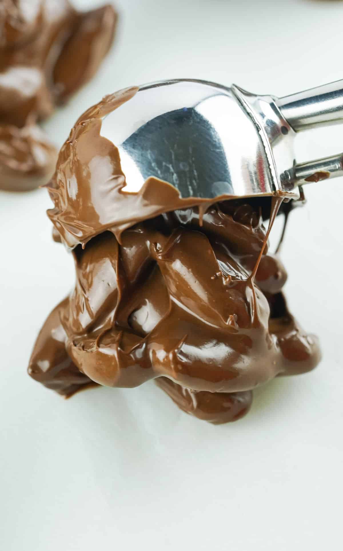 Scooping the chocolate almond mixture with a cookie scoop and placing it on parchment paper