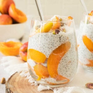 Fresh apricot and chia pudding served in a glass with a bowl of apricots in the background