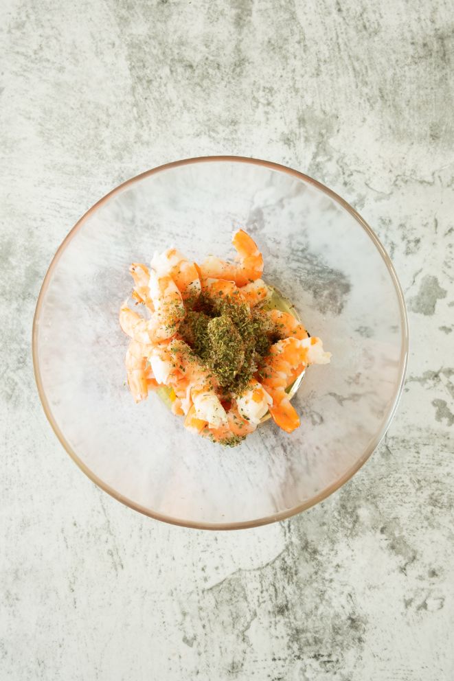 Add the peeled and deveined shrimp to a large bowl and add the oil and herbs