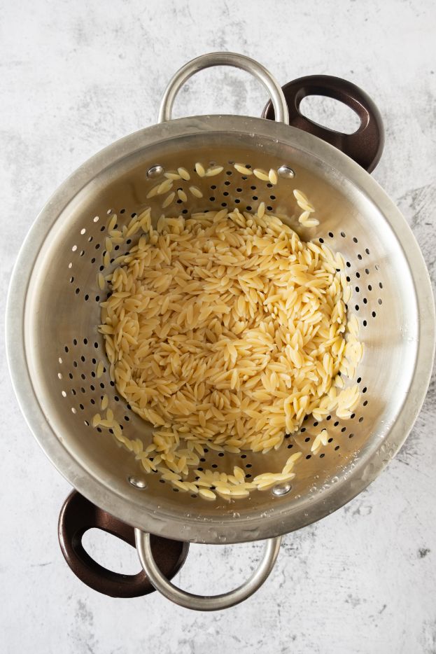 Rinsing cooked orzo in a colander to remove the starches