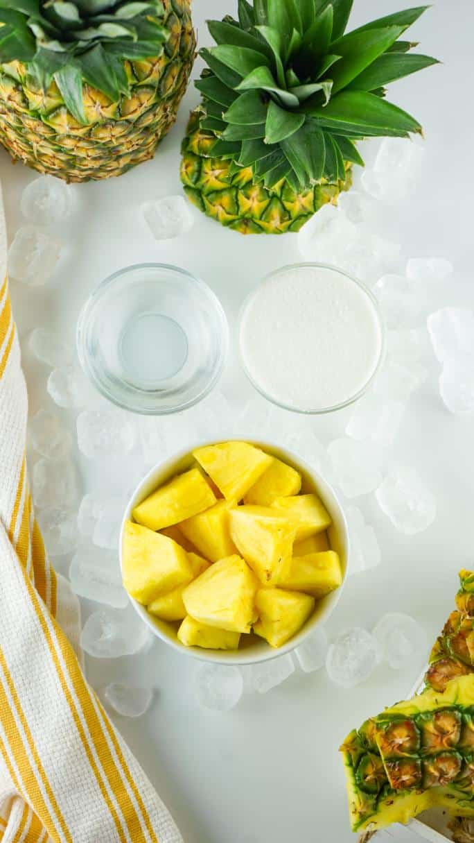 An overhead shot of pineapple, ice and sugar served in small bowls