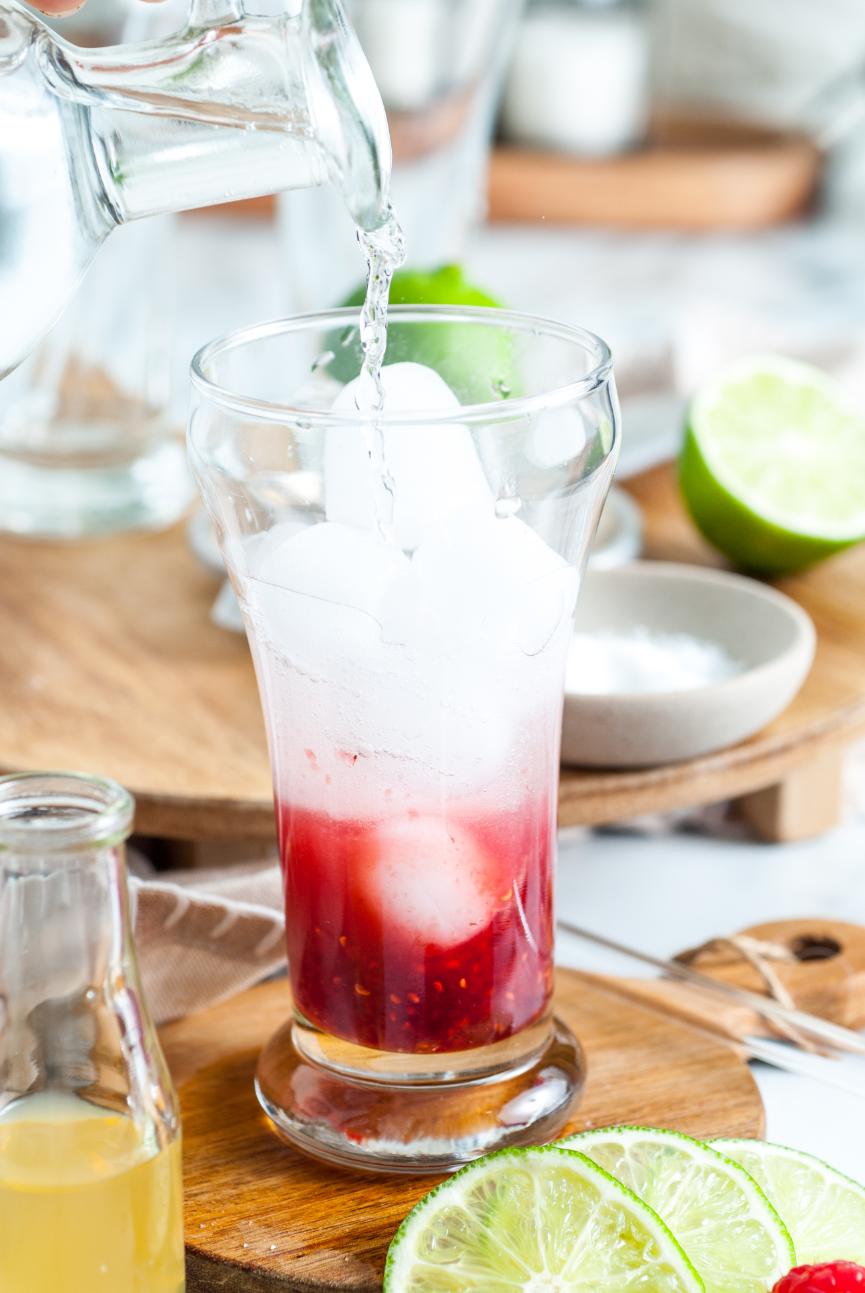 Ice and sparkling water being added to a cocktail