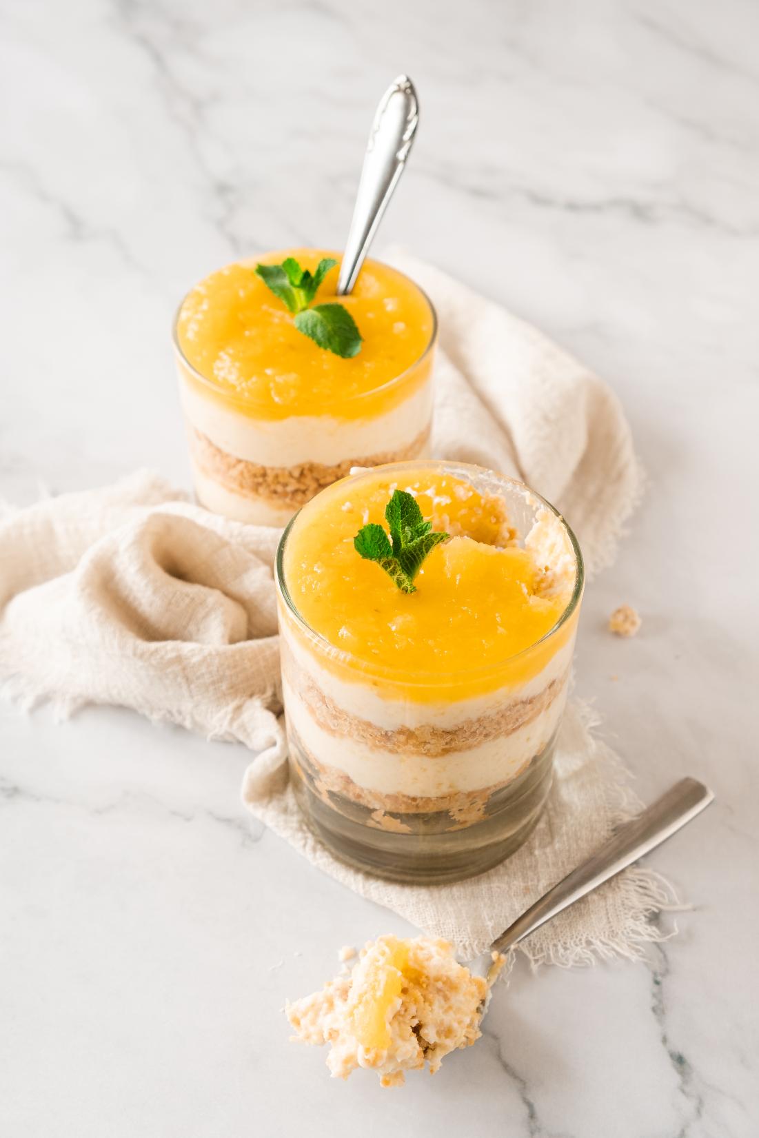 A spoon taking a spoonful of cheesecake out of a layered cheesecake jar