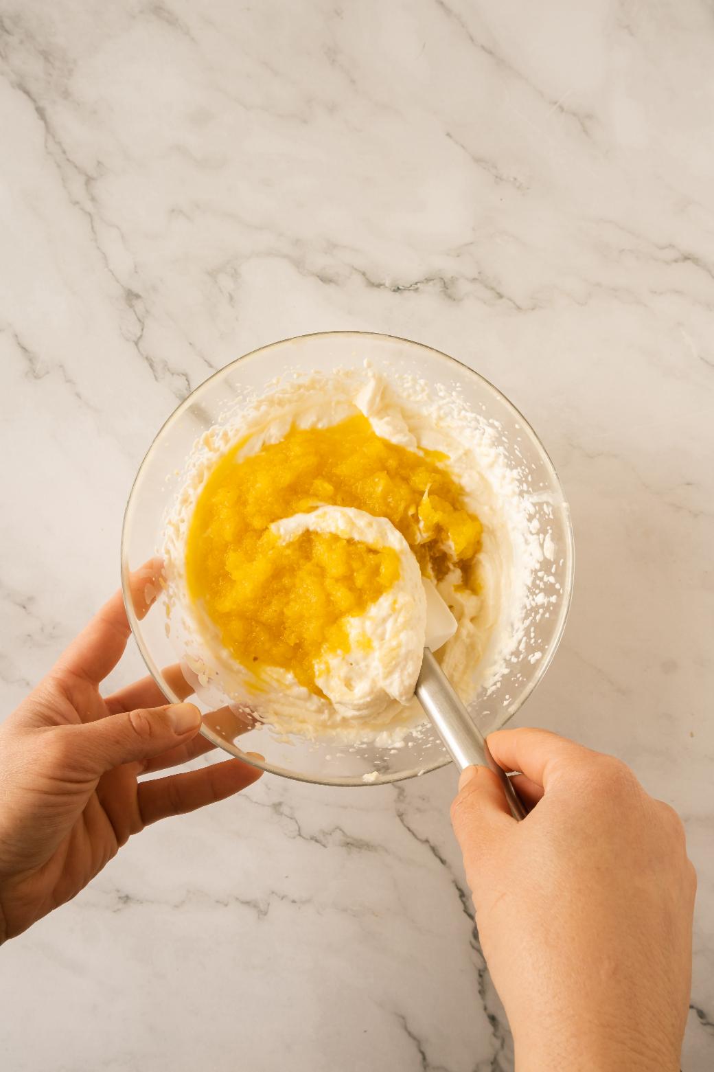 Pineapple being folded into a cheese cream mixture