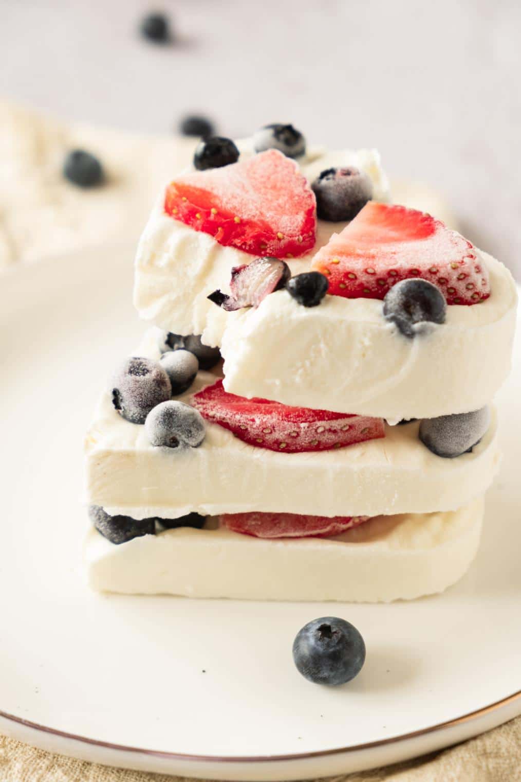 up close shot of 3 pieces of frozen greek yogurt berry bites stacked on top of each other with a bite taken out of the top piece