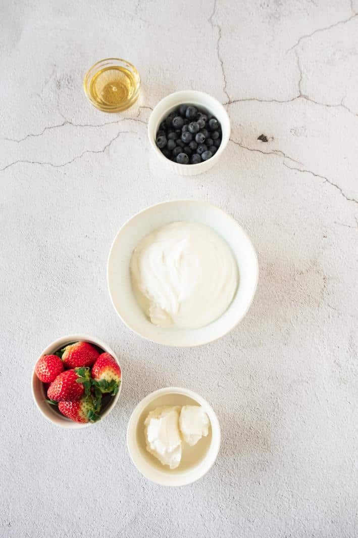 Overhead ingredient shot of ingredients needed to make a yogurt bark, with all ingredients served in small white bowls