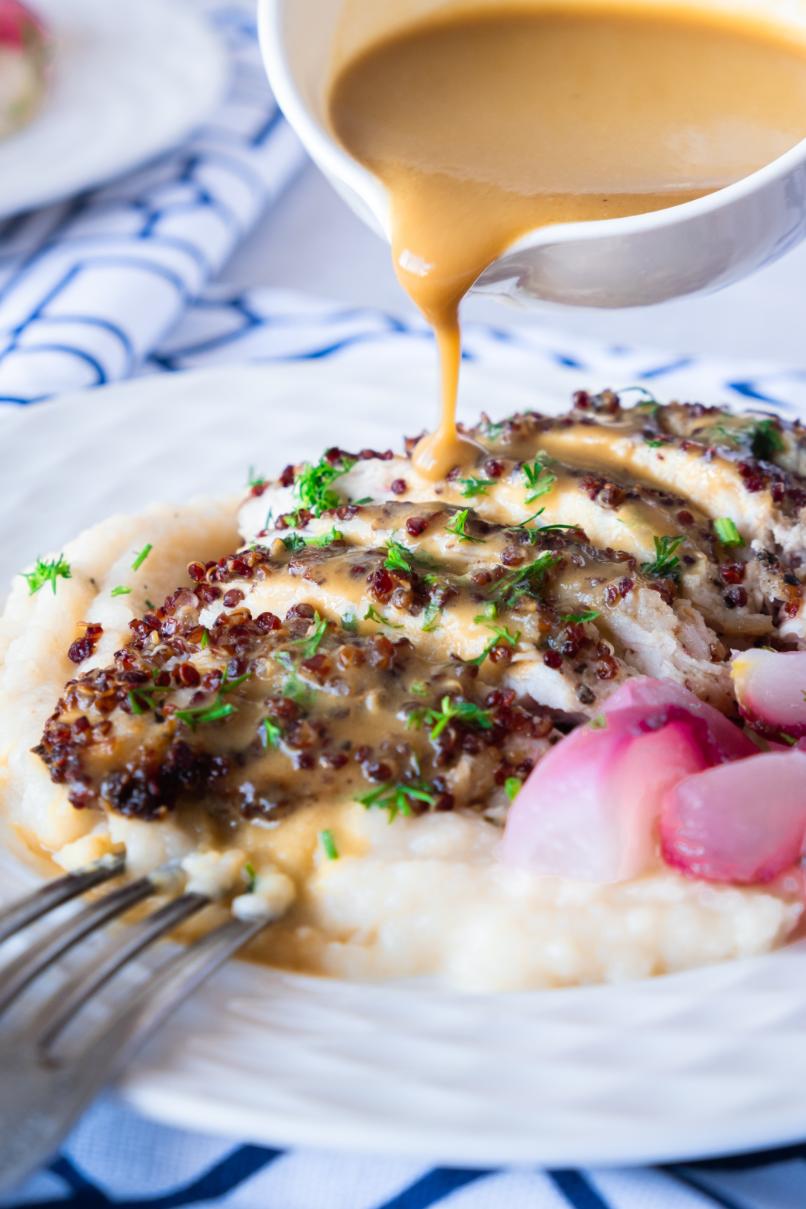 Photo of fried quinoa chicken on mashed potatoes with mustard sauce being poured on top