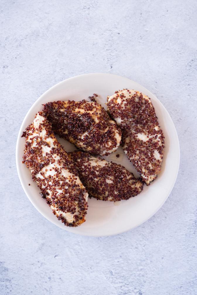 Photo of cooked chicken breasts coated in red quinoa