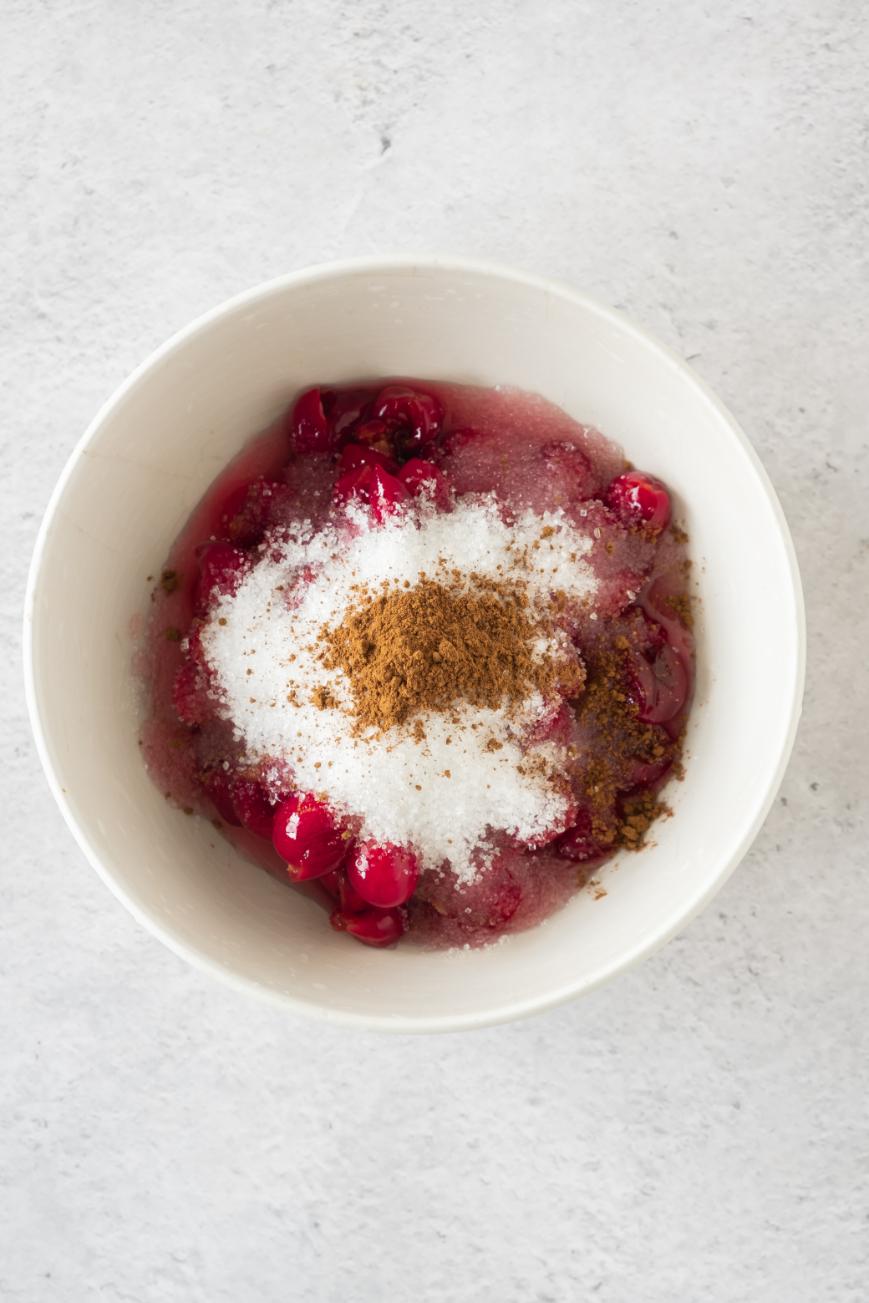 A bowl of cherry chia pudding topped with sugar and a dusting of cinnamon, poised for a sweet recipe.