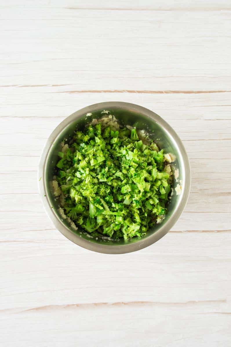 Cooked broccoli chopped into a small stainless steel bowl
