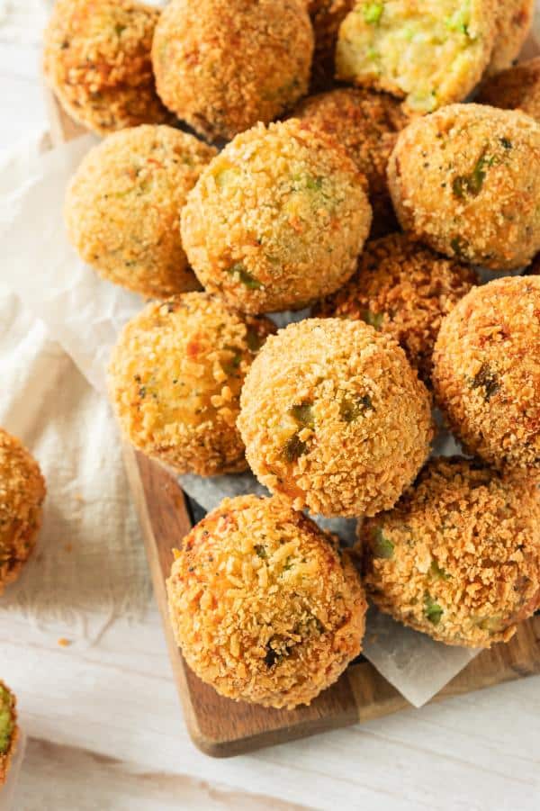 Overhead shot of panko crusted broccoli bites stacked on a wooden board