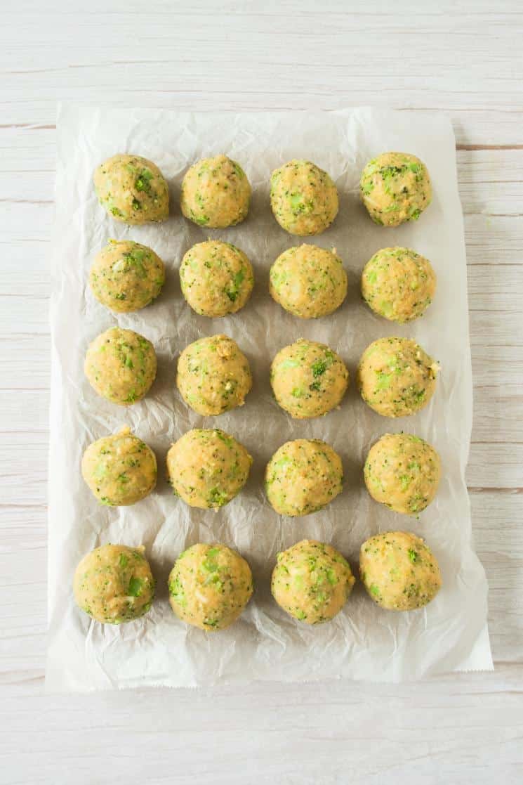 Broccoli cheese balls rolled into even sized balls and arranged on parchment paper