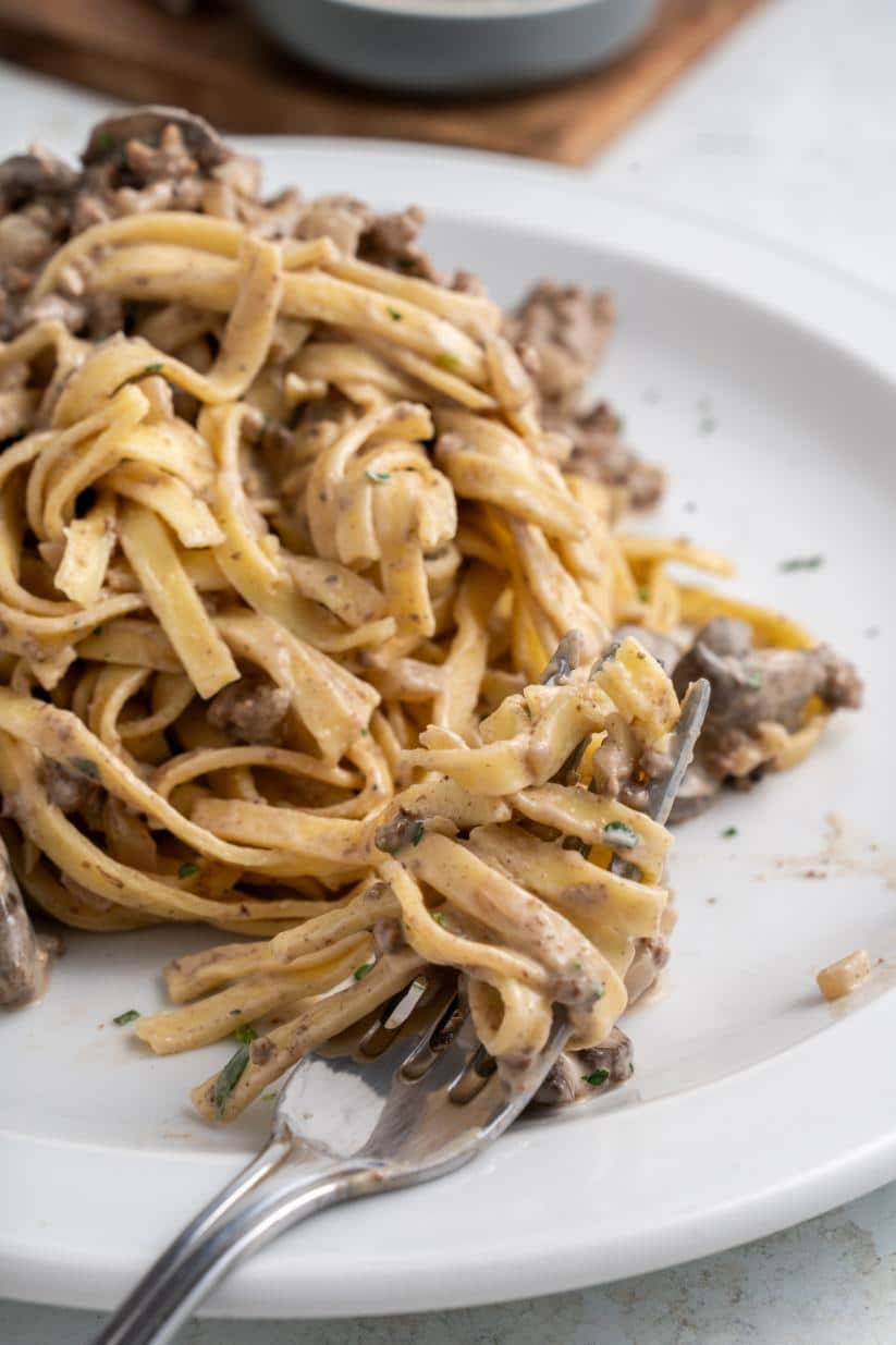 Up close shot of buttered noodles topped with a creamy ground beef and mushroom sauce