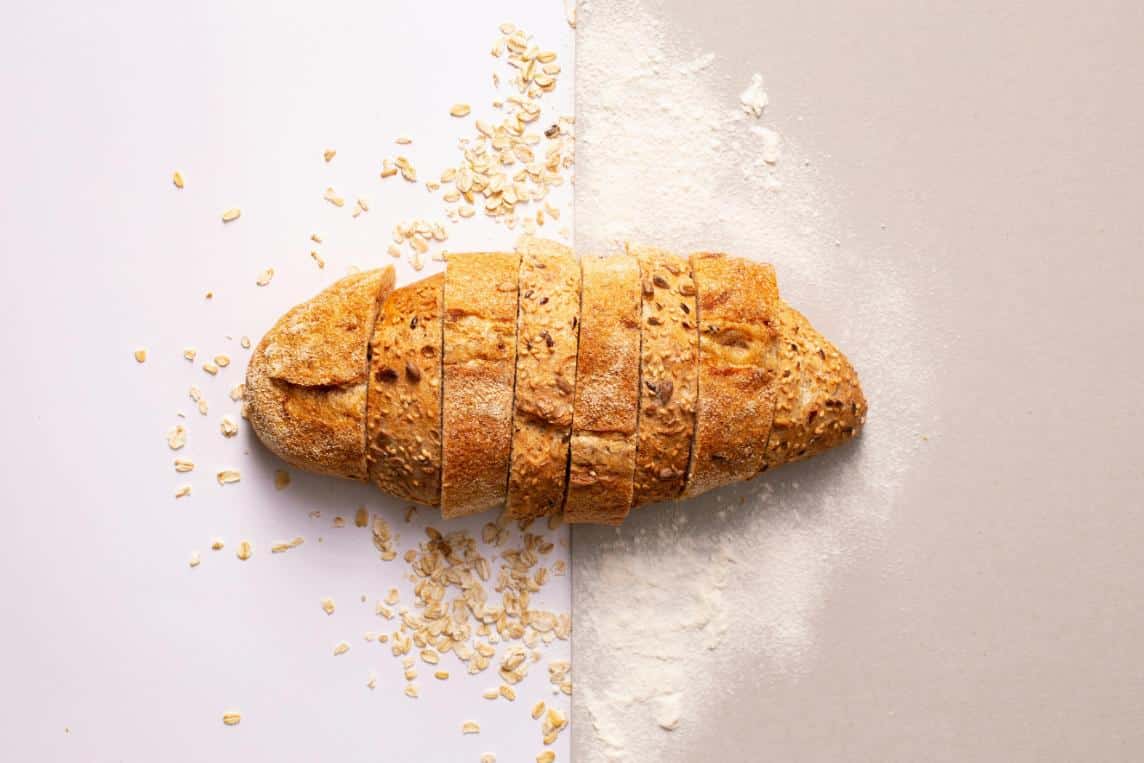 a loaf of homemade bread sliced and dusted with oats