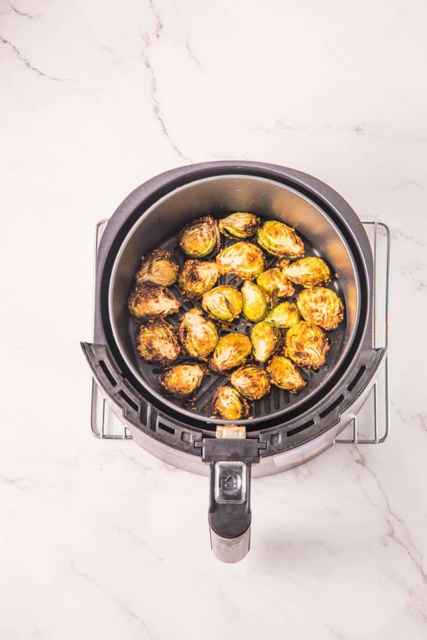 Overhead shot of cooked Brussels sprouts in the basket of an air fryer.