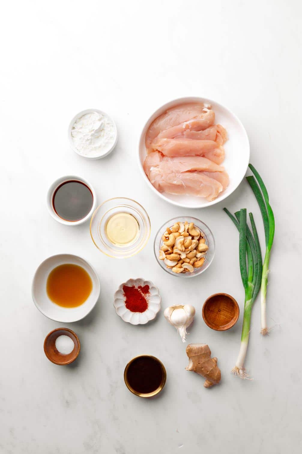 Overhead ingredient shot. All ingredients are served in small white bowls and there are 2 fresh spring onions on the side.
